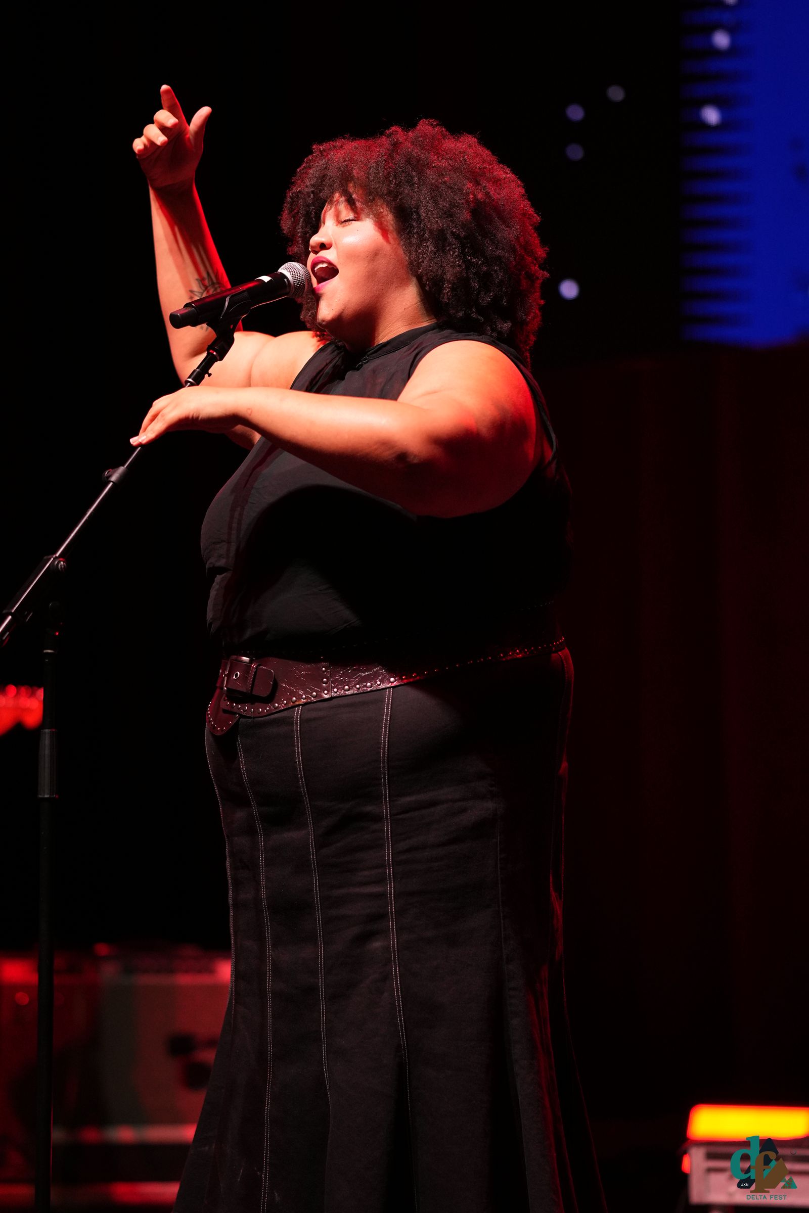 Performer singing on stage, fist raised